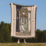 Person holding a Tarot card-themed blanket with 'The High Priestess' design outdoors.