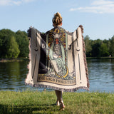 Person holding a tarot-themed blanket by a lake