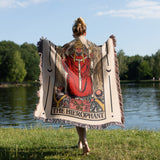 Person holding a Tarot card-themed blanket by a lake