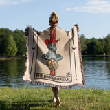 Person holding a tarot card-themed blanket by a lake