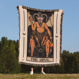 Person holding a tapestry with 'The Devil' design in a field