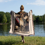 Person holding a tarot card-themed blanket by a lake