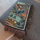 Decorative blanket with a Libra design  on a gray couch.