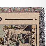 Close-up of a woven blanket with a colorful fringe, featuring intricate designs and text.