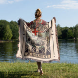 Person holding a tarot card-themed blanket by a lake