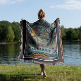 Person holding a colorful Aquarius-themed blanket by a lake