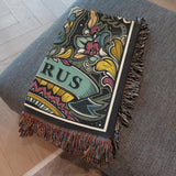 Decorative blanket with colorful patterns and 'TAURUS' text on a gray surface
