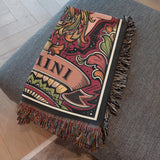 Decorative blanket with intricate patterns and tassels on a gray surface