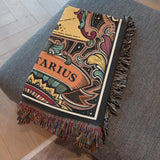 Decorative blanket with 'Sagittarius ' design on a gray surface
